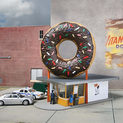 Walthers Cornerstone Hole-In-One Donut Shop model with giant donut sign in HO scale layout.