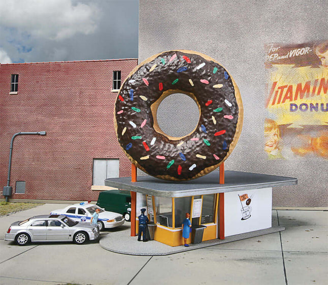Walthers Cornerstone Hole-In-One Donut Shop model with giant donut sign in HO scale layout.