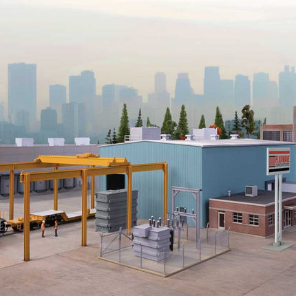 HO scale Transformer Factory model with overhead crane, substation, and industrial buildings in city backdrop.