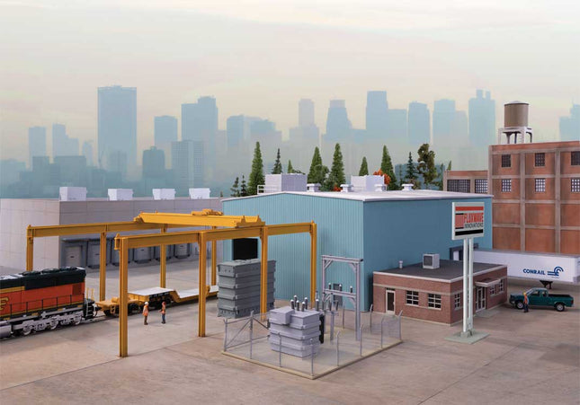 HO scale Transformer Factory model with overhead crane, substation, and industrial buildings in city backdrop.