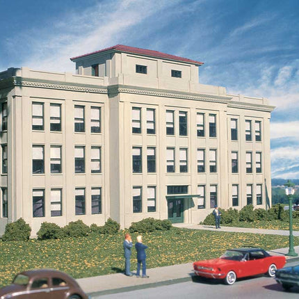 Walthers HO scale Ford Central Office Building kit displayed in a scenic urban setting with classic cars.