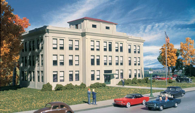 Walthers HO scale Ford Central Office Building kit displayed in a scenic urban setting with classic cars.