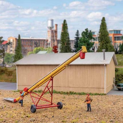 HO scale utility auger model kit with workers in a detailed outdoor setting, featuring a building and vehicles.