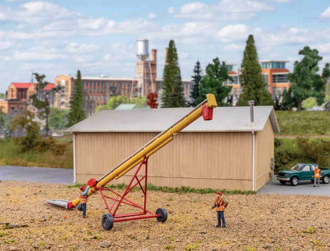 HO scale utility auger model kit with workers in a detailed outdoor setting, featuring a building and vehicles.