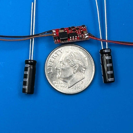 NixTrainz 204 Power Bridge III with capacitors and a quarter for size reference on a blue background.